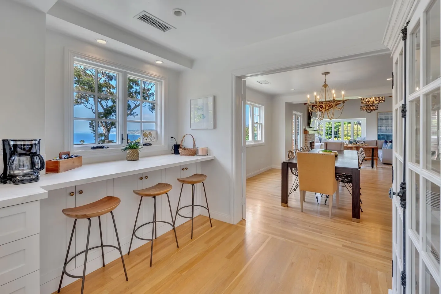 Bright kitchen bar area with stools and view into dining room.