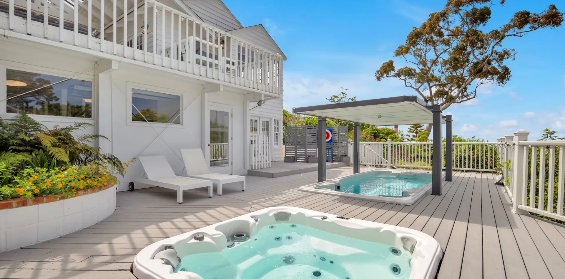 Modern backyard with hot tub, lounge chairs, and basketball hoop.