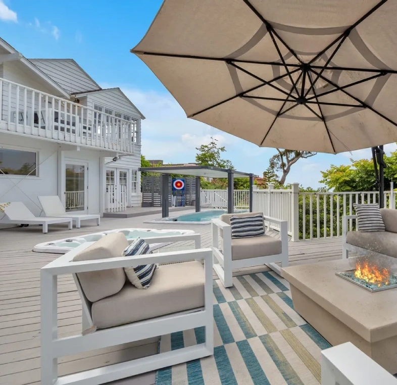Modern outdoor patio with cozy seating, fire pit, and large umbrella.