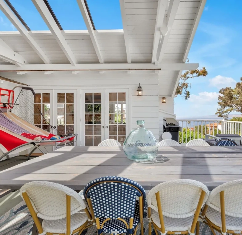 Outdoor patio dining area with chairs and a play area under a pergola.