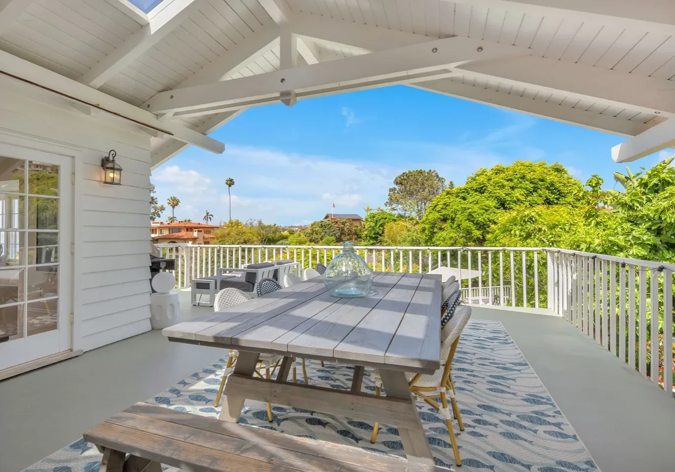 Cozy outdoor seating area on a sunny porch with scenic greenery views.