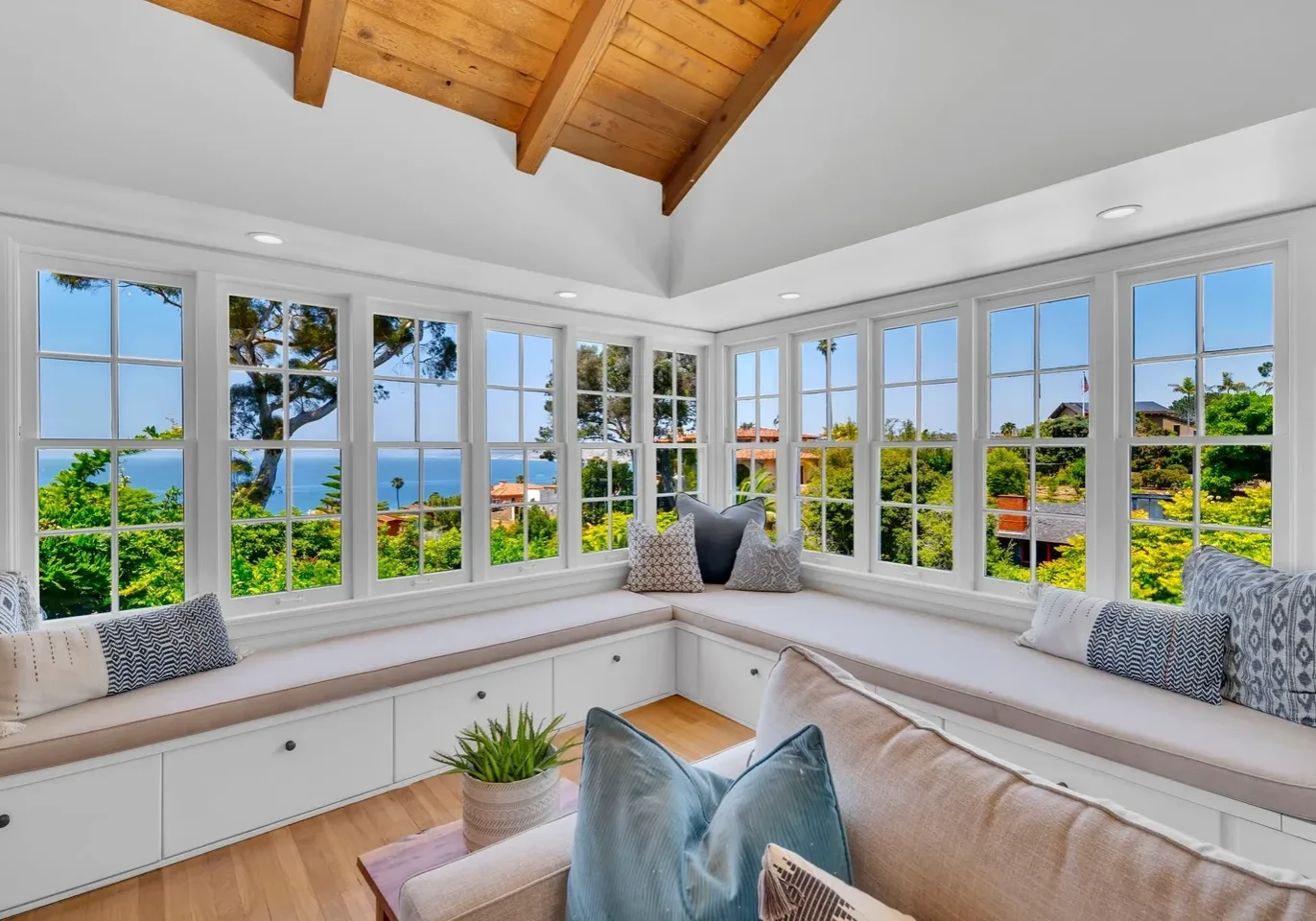 Cozy window nook with cushioned seating overlooking a scenic garden and water views.